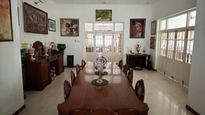 A dining room with a long table, chairs, a ceiling fan, and artwork on the walls. - Nora Lyn - Colombo (Colombo)