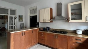A kitchen with wooden cabinets, a gas stove, a ceiling fan, and a window. - Nora Lyn - Colombo (Colombo)
