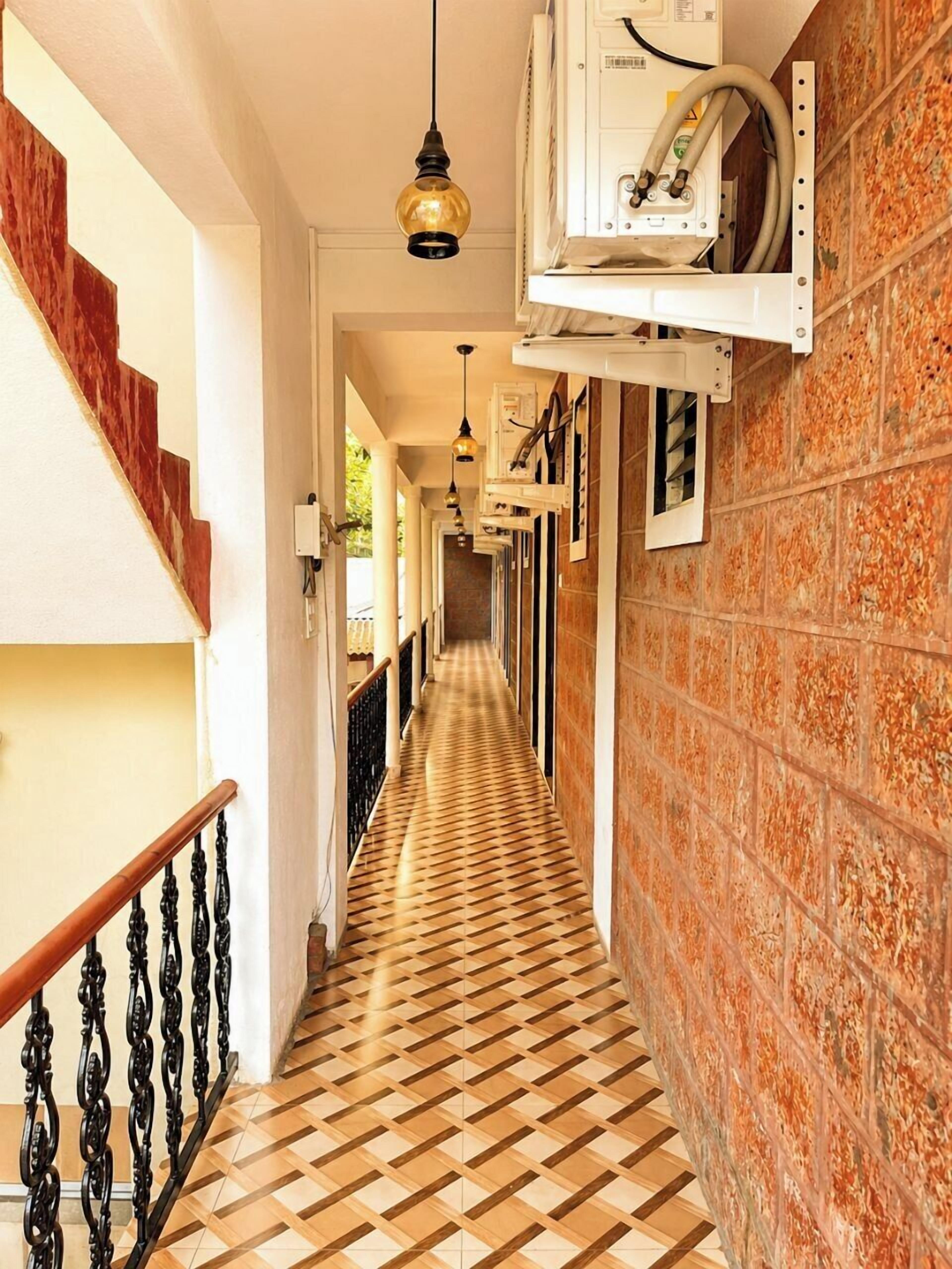 A hallway with patterned flooring, a wooden staircase, and a metal railing.