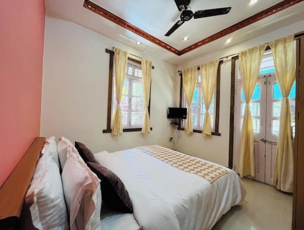 Un dormitorio con cama, ventilador de techo y ventanas con cortinas.