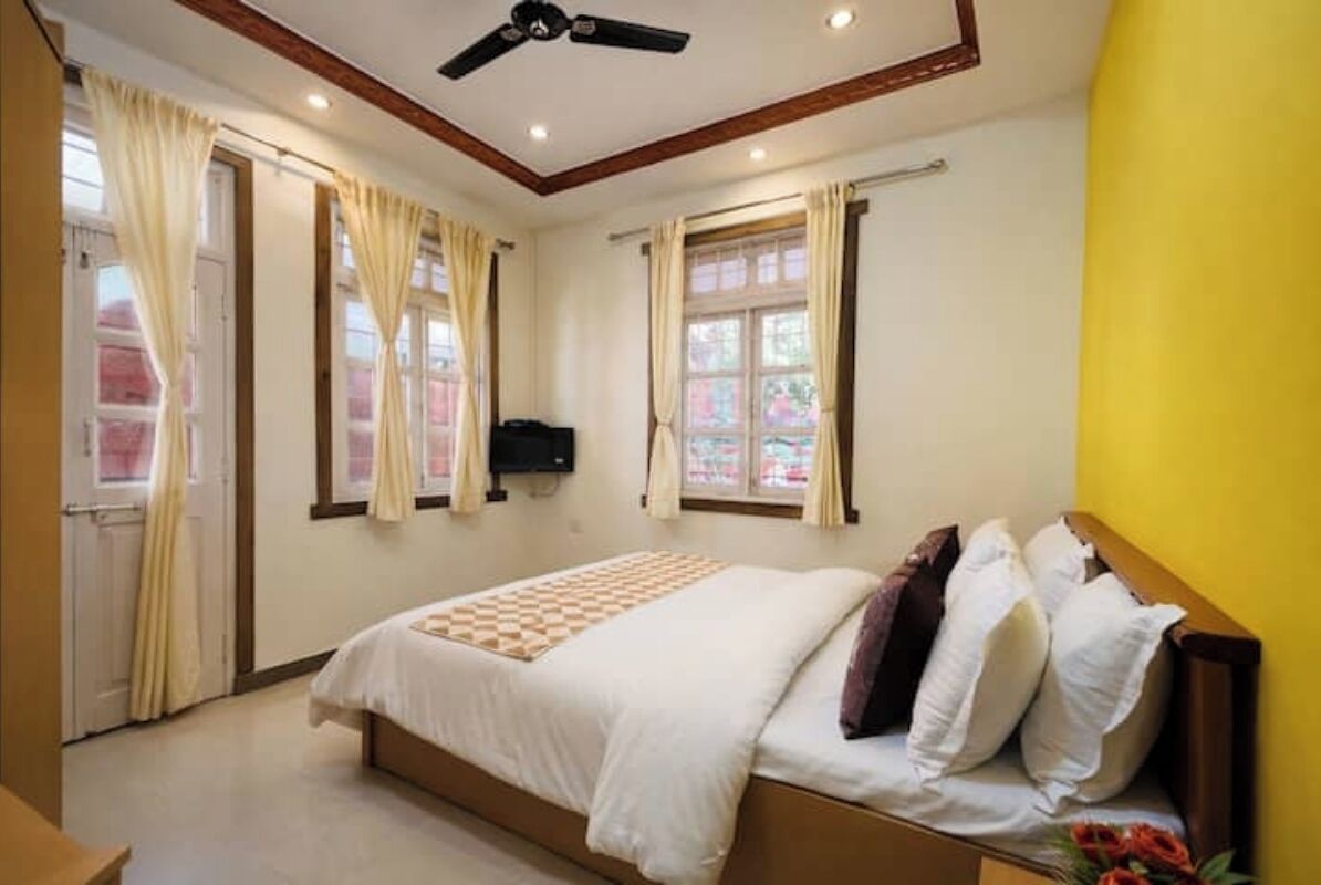 A bedroom with a bed, curtains, a ceiling fan, and a window.