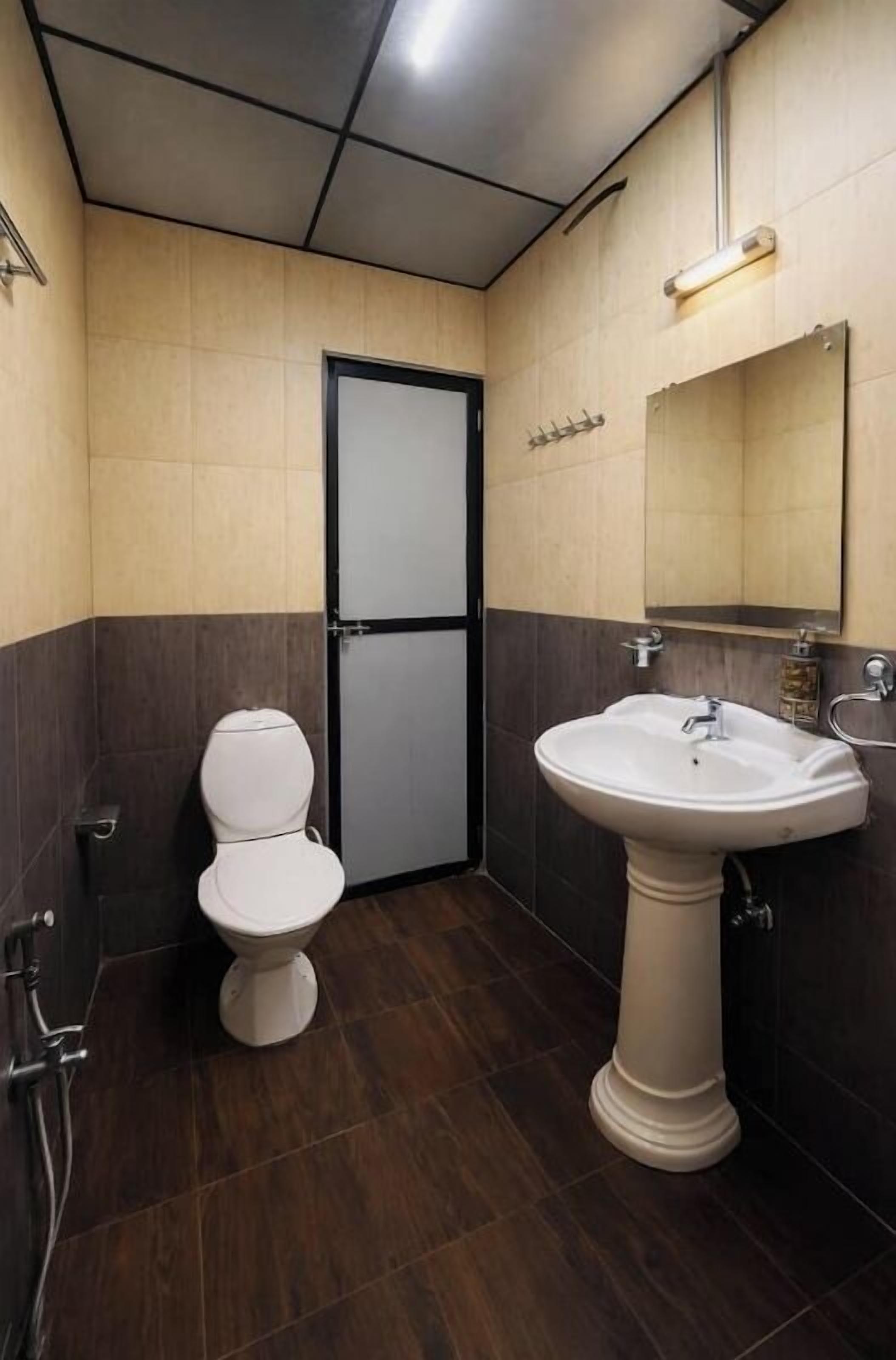A bathroom with a toilet, sink, and mirror.