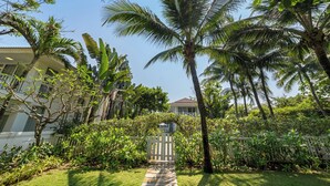 A pathway leading to a gated entrance surrounded by lush greenery and palm trees. - Pool Villas Resort (Da Nang)