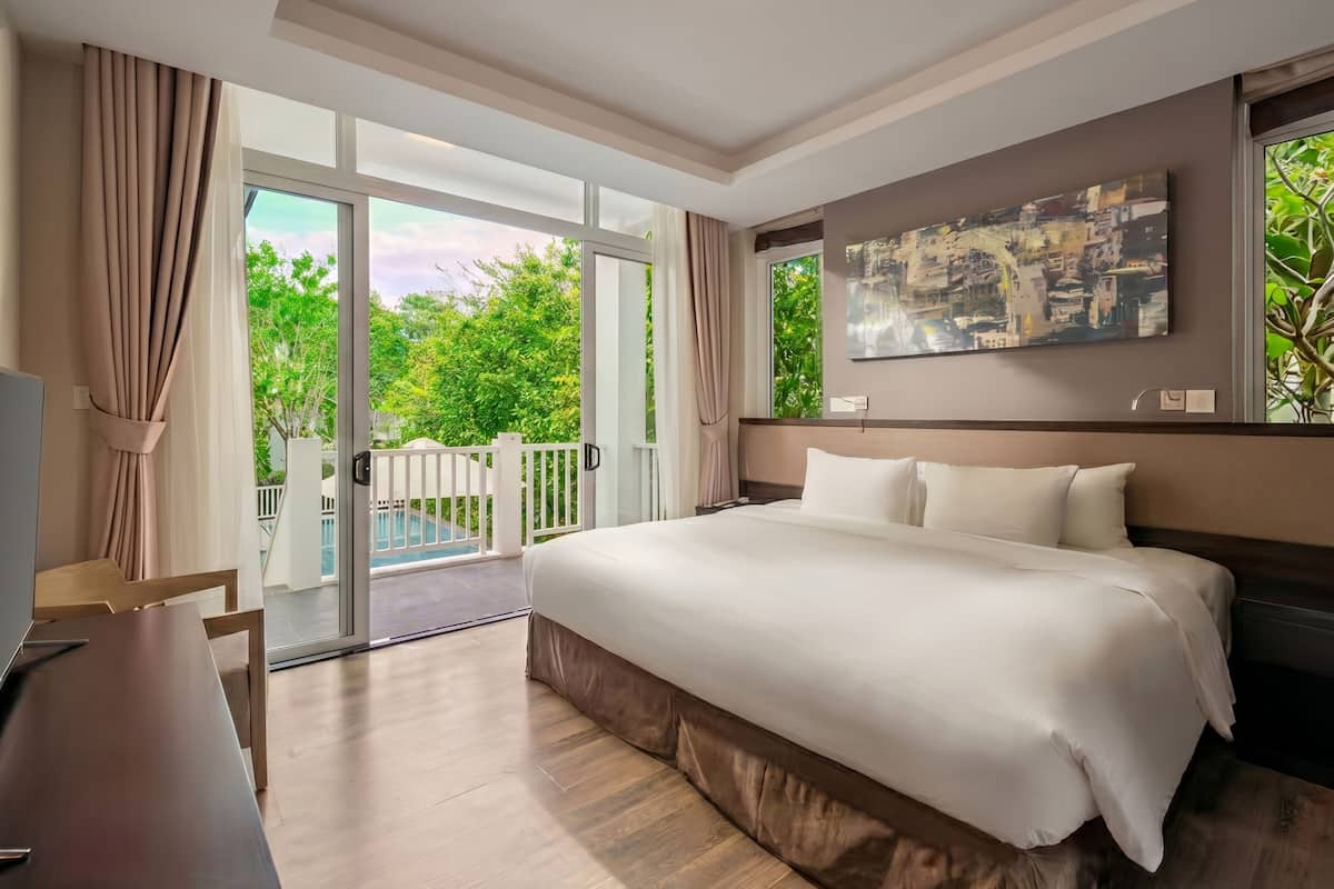 Una habitación de hotel con una cama grande, televisión y balcón con vista a la piscina.