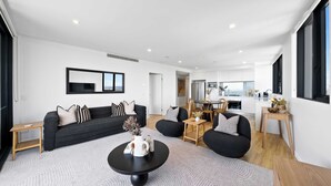 Een moderne woonkamer met een bank, salontafel en een eethoek met stoelen.