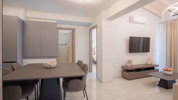 Un salon moderne comprenant une table à manger, des chaises, un téléviseur à écran plat et un canapé.