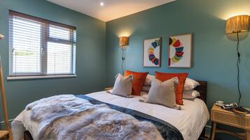 Ein Schlafzimmer mit Bett, Kissen, Teppich, Nachttisch, Lampe und Bildern an der Wand.