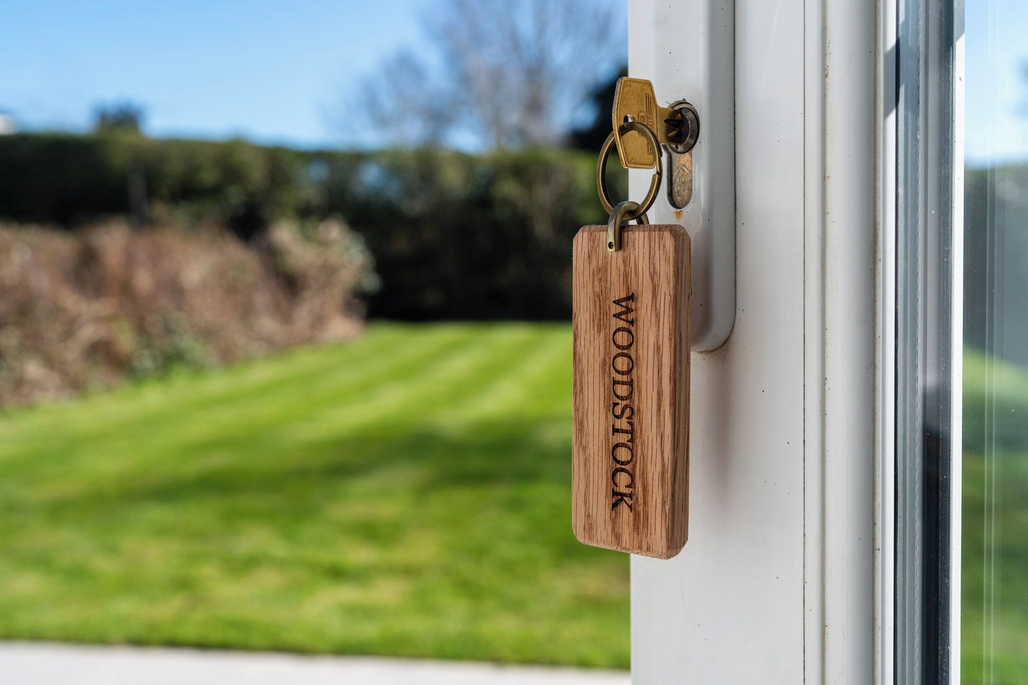 A wooden keychain with 'WOODSTOCK' engraved on it, attached to a door handle.