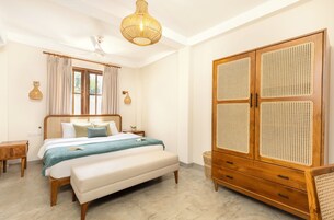 A bedroom with a bed, bedside tables, a wardrobe, and a hanging light fixture.