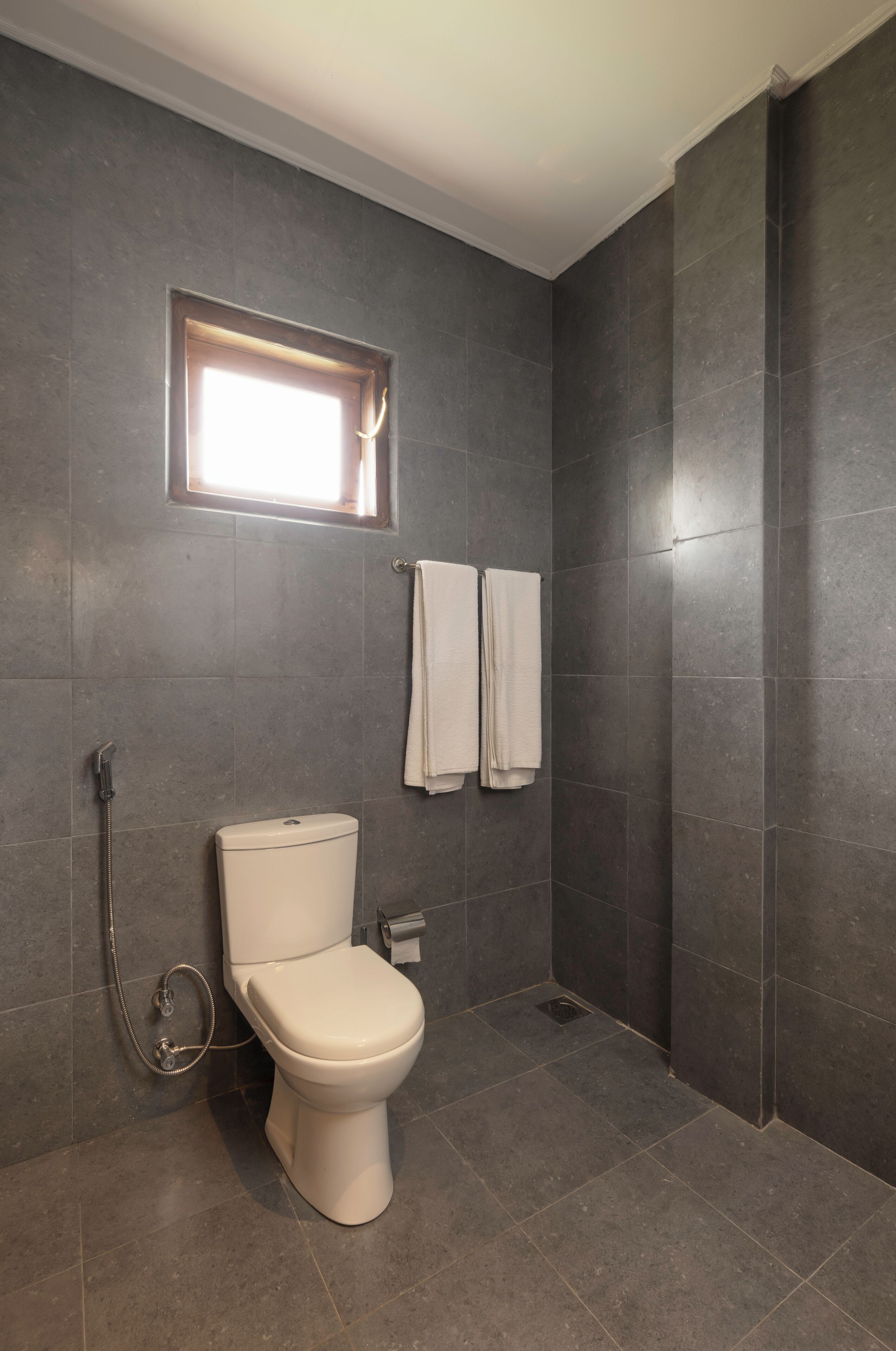 Een badkamer met toilet, douche en raam.