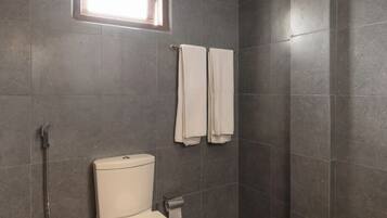 A bathroom with a toilet, a shower, and a window.