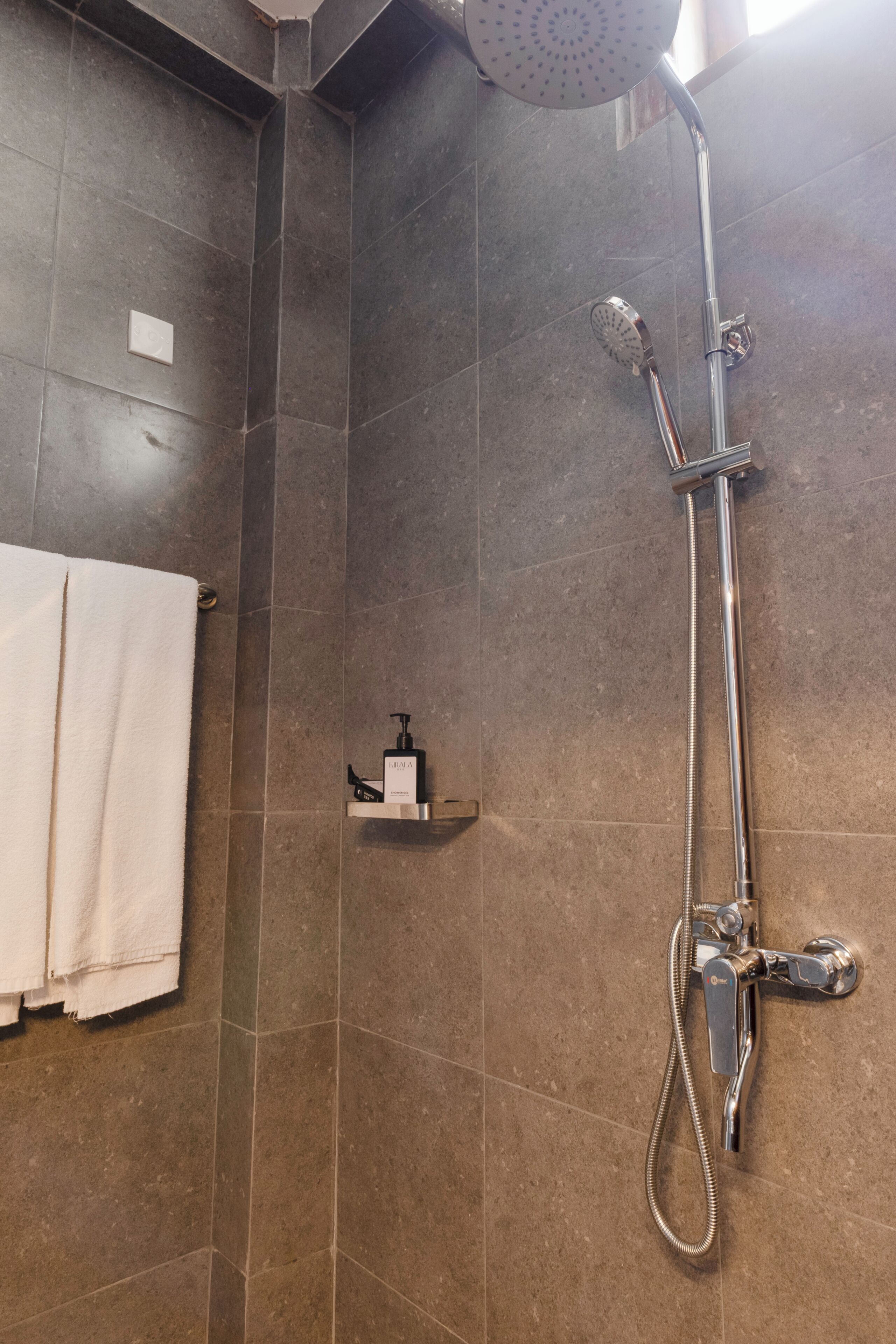 A shower with a handheld showerhead and a wall-mounted faucet.