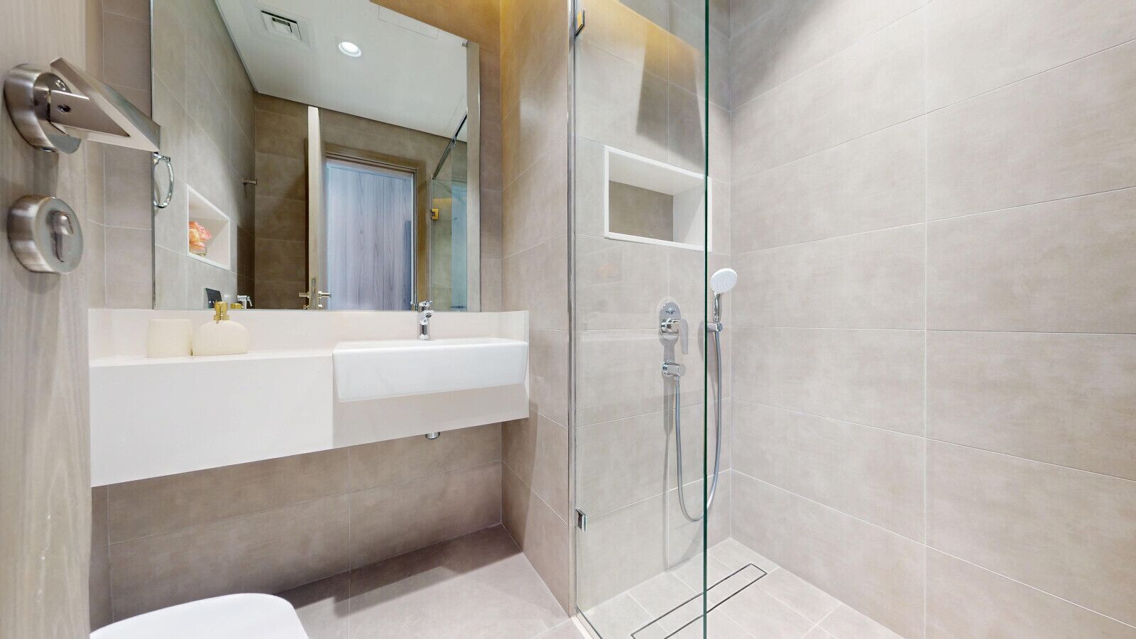 Un bagno moderno con cabina doccia in vetro, un lavandino bianco e uno specchio sopra il mobile.