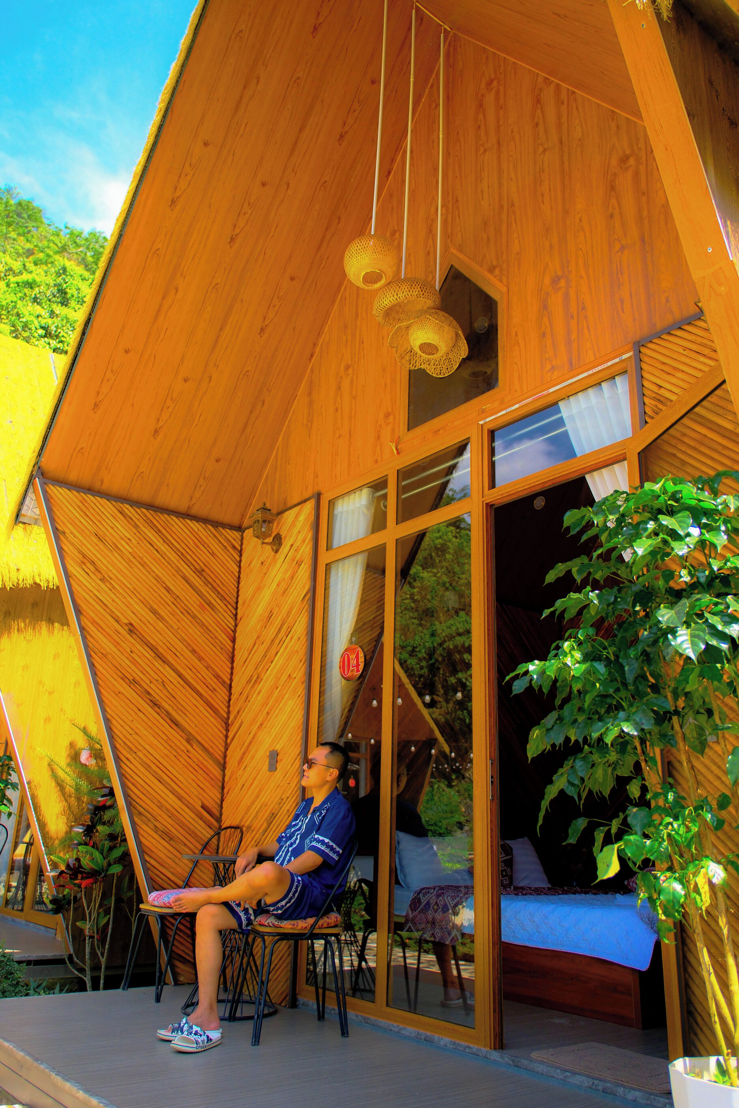Une cabane en bois avec un lit, une chaise et une plante en pot.