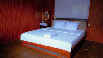 A neatly made bed with white linens, a wooden headboard, and a small bedside table with a lamp.