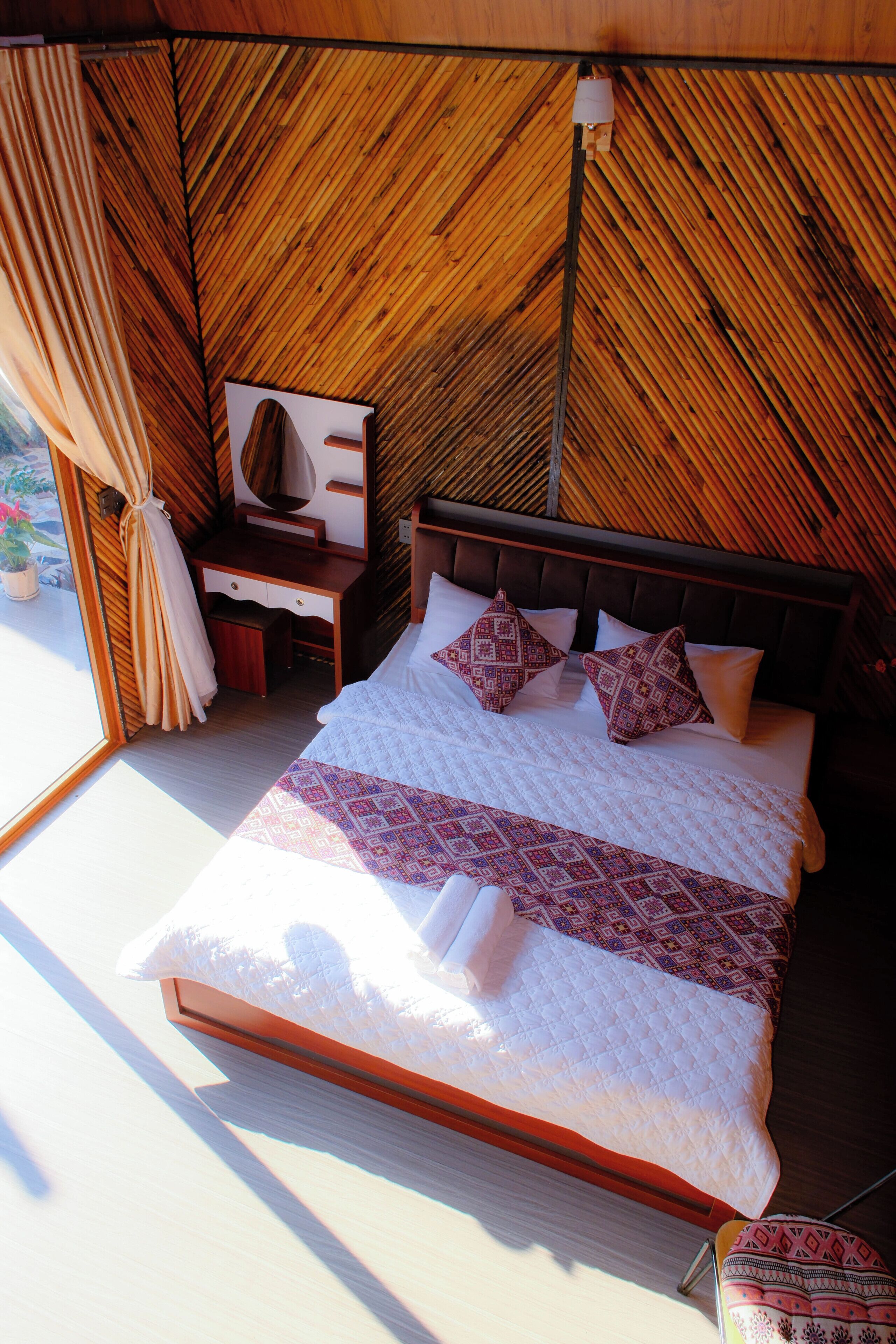 A bedroom with a bed, pillows, a nightstand, and a mirror.