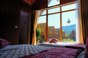 Une chambre avec une grande fenêtre, un lit et une vue sur une maison.