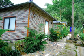 A brick building with a tiled walkway, surrounded by lush greenery. - Hagiang Golden Sun Retreat (Ha Giang)