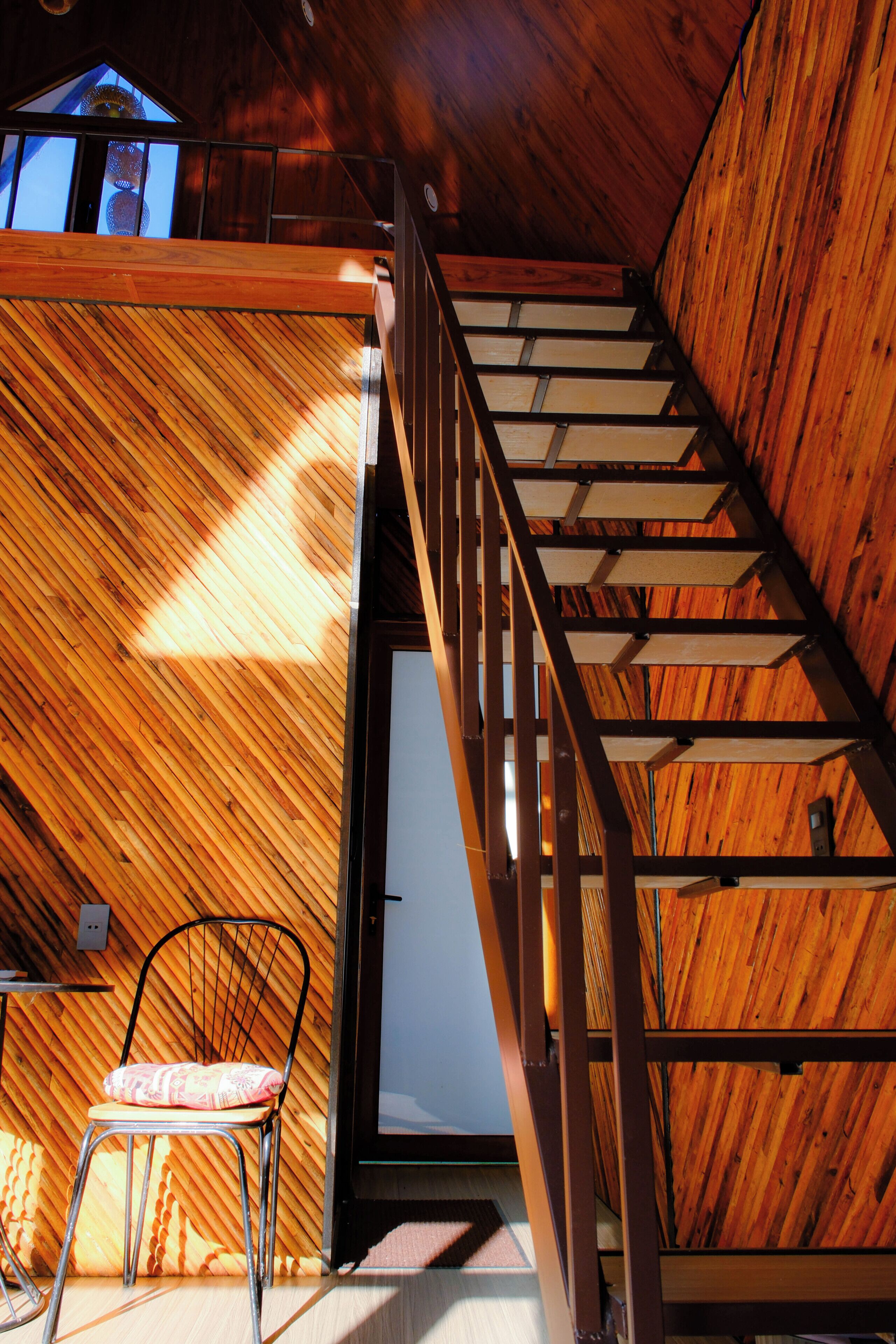 Ein Holzinnenraum mit Treppe, einem Sessel und einem Bett.