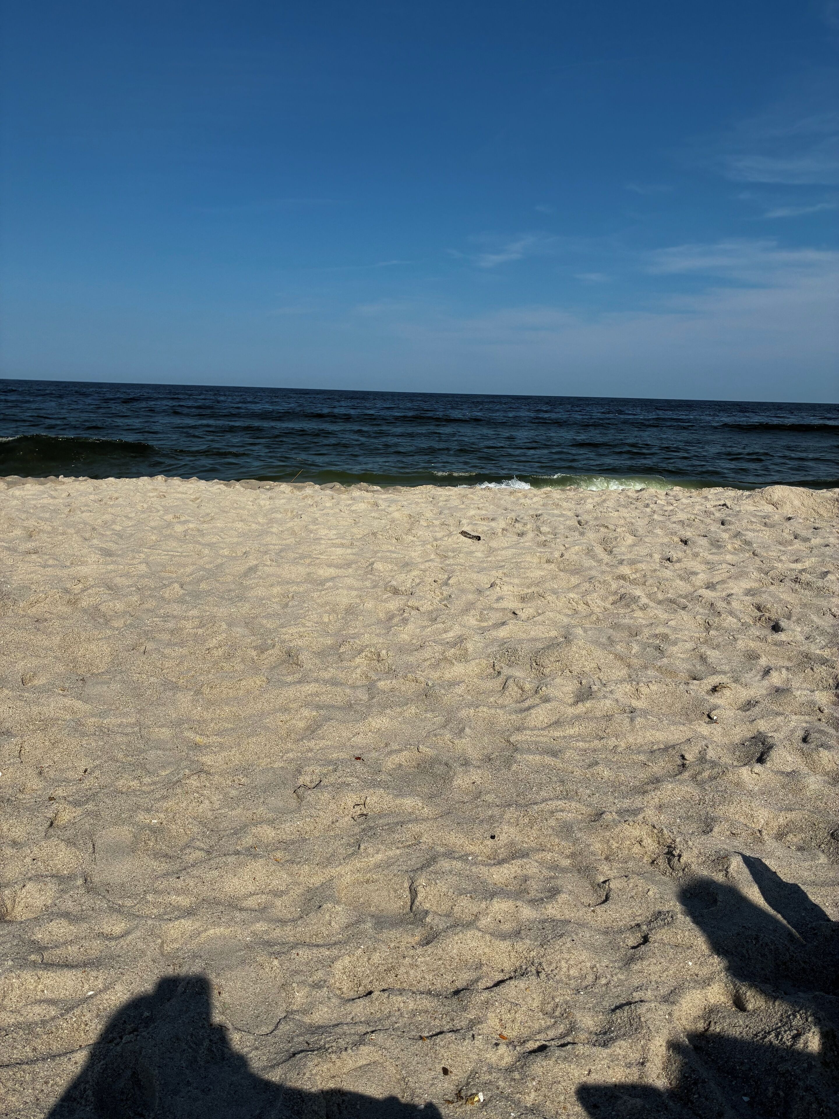 A sandy beach with footprints leading to the water.