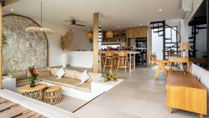 A modern interior with a stone wall, a wooden dining area, and a staircase. - New Villa in Kerobokan - 5 Min to Canggu (Badung)