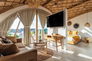 Una camera moderna con una grande TV, un divano, un tavolo da pranzo e un letto con vista.