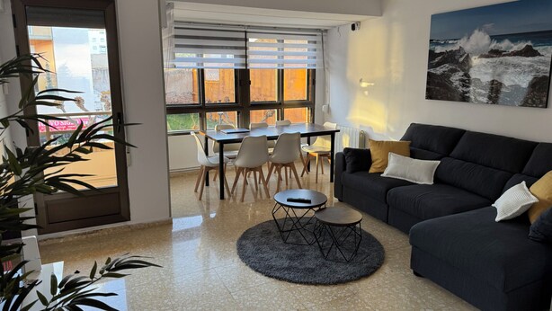 Un salon avec un canapé foncé, une table basse ronde et un coin repas comprenant une table et des chaises.