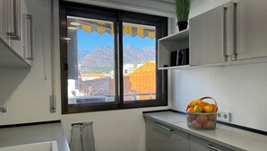 Une cuisine moderne avec une fenêtre donnant sur les montagnes, un évier et un panier de fruits.