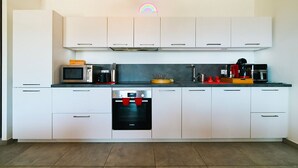 Uma cozinha moderna com armários brancos, micro-ondas, cafeteira e máquina de lavar louça.