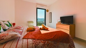 Quarto com cama, televisão, escrivaninha e janela com vista.