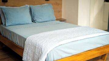 A bed with a wooden frame, a light blue mattress, and matching pillows.