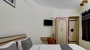 Una habitación de hotel con cama, escritorio, televisor y armario.
