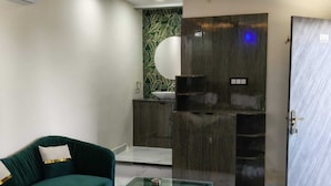 Una sala de estar moderna con un sofá verde, una mesa de centro de vidrio y un piso de mármol.