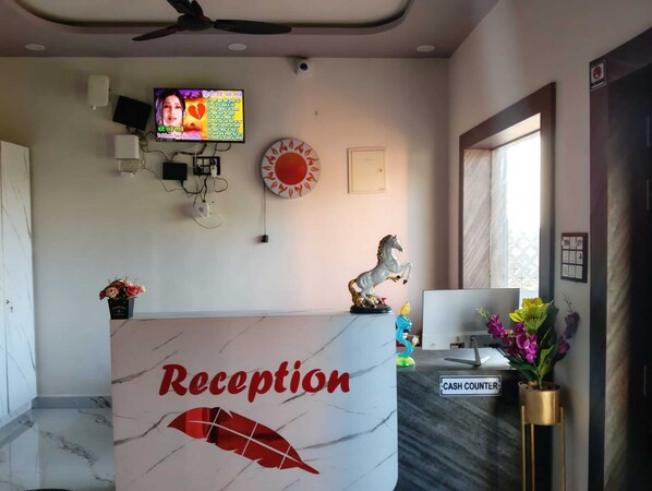 A reception desk with a sign, a television, a wall-mounted clock, and a decorative horse statue.