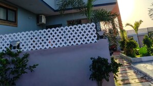 Un edificio moderno de varios pisos con balcones, unidades de aire acondicionado y una valla con diseño.