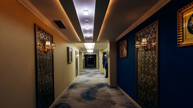 Un pasillo de hotel con paredes estampadas, apliques de pared y suelo alfombrado.