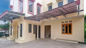 A two-story building with a covered patio area, multiple windows, and a staircase leading to the upper floor. - Stylish DBL Suite Escape W/ Free Wifi and Parking (Megamendung)