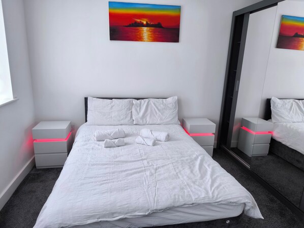 A modern bedroom with a bed, white pillows, and nightstands.