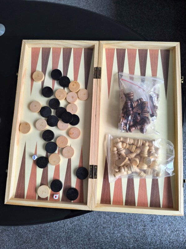 Un juego de mesa con tablero a cuadros, fichas y bolsas con piezas adicionales.