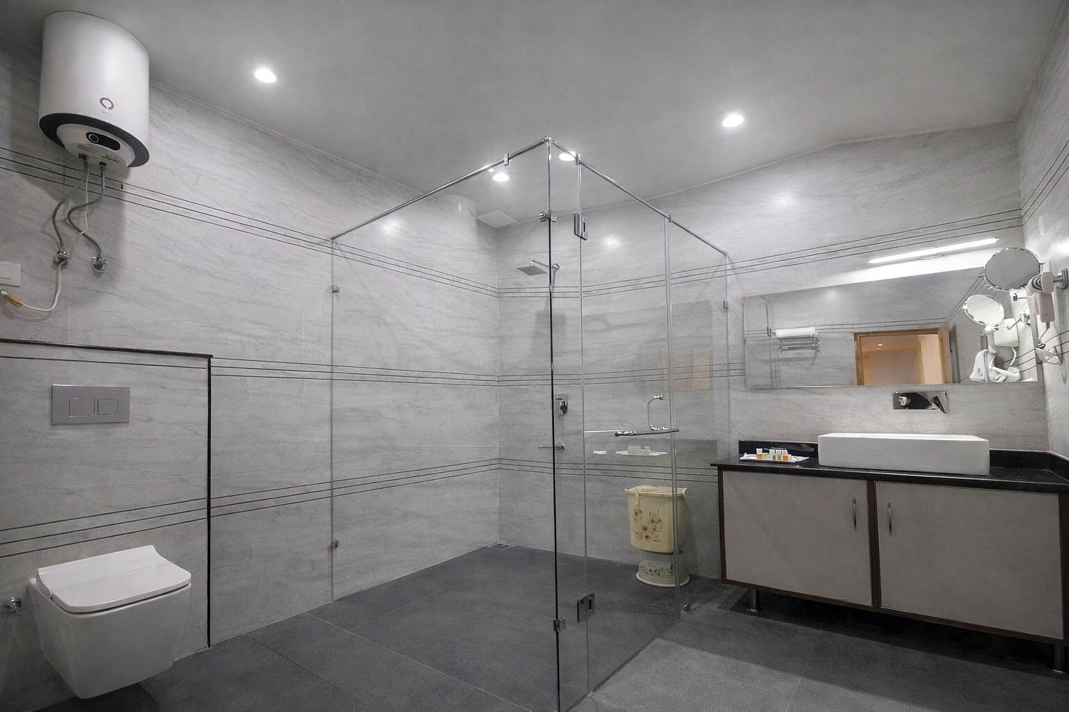 Un baño moderno con ducha de vidrio, inodoro, lavabo con espejo y armario.
