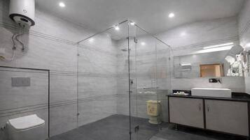 Un baño moderno con ducha de vidrio, inodoro, lavabo con espejo y armario.