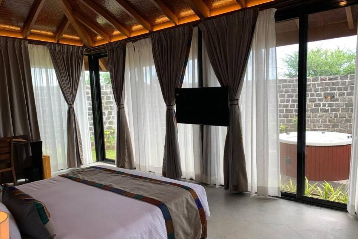 A bedroom with a bed, a flat-screen TV, and a sliding glass door leading to an outdoor hot tub.