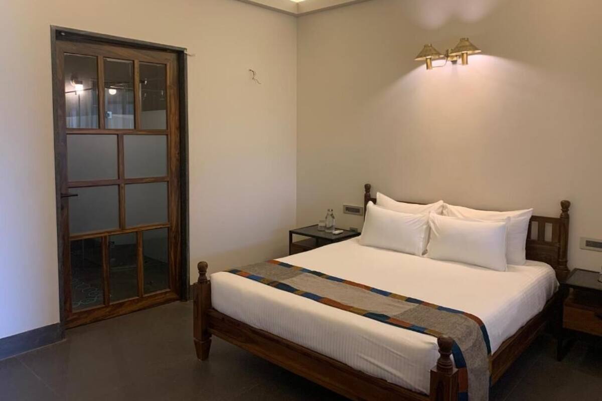 A bedroom with a wooden bed, a nightstand, a lamp, and a sliding glass door.