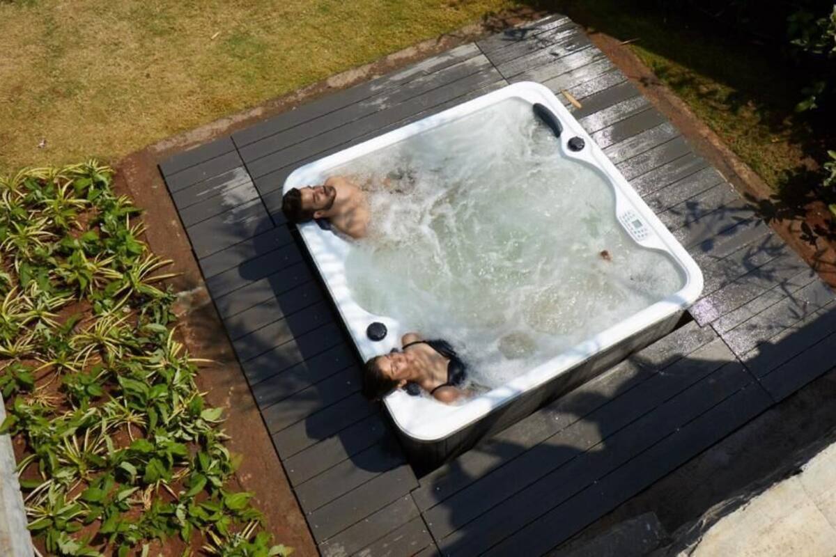 A hot tub on a wooden deck with plants around it.