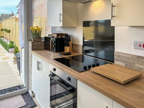 A modern kitchen with a built-in oven, a stainless steel refrigerator, and a wooden countertop.