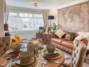 A furnished living room with a dining area, a world map on the wall, and a view of buildings outside.