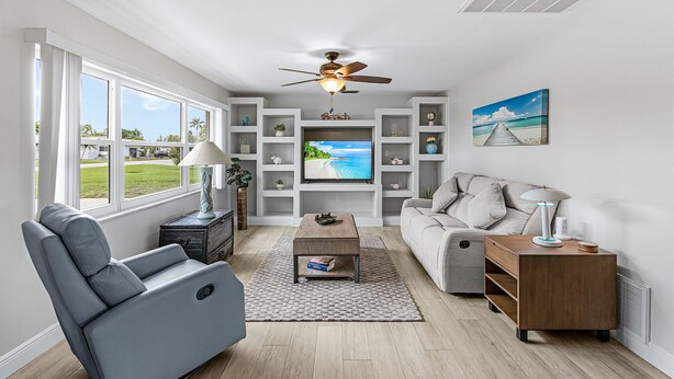 A living room with a TV, sofa, and a ceiling fan. - 5 min to Beach - Newly Renovated (Cape Coral)