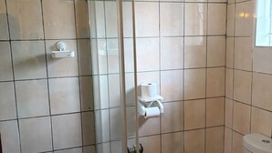 A bathroom with a toilet, a glass shower enclosure, and a toilet paper holder on the wall. - Perfect 3 x 1-bedroom Rooms in beautiful Sasolburg for your getaway (Sasolburg)