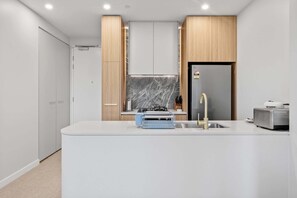 A modern kitchen with a central island, a built-in oven, and a stainless steel sink.