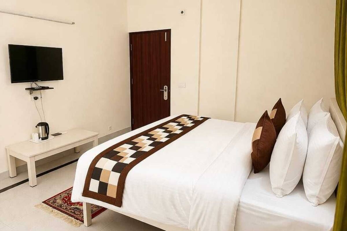 Quarto de hotel com cama, televisão, escrivaninha e guarda-roupa.